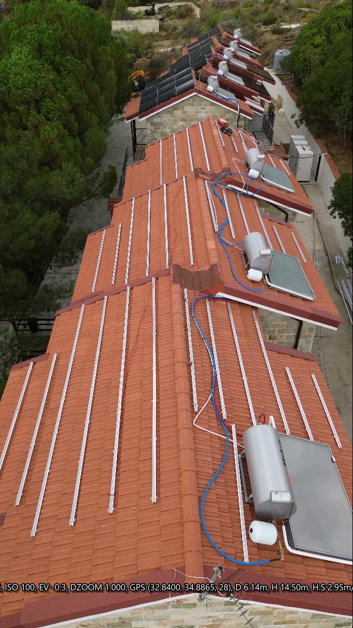 Aerial installation-stage view of mounting rails and solar panels on several hotel buildings
