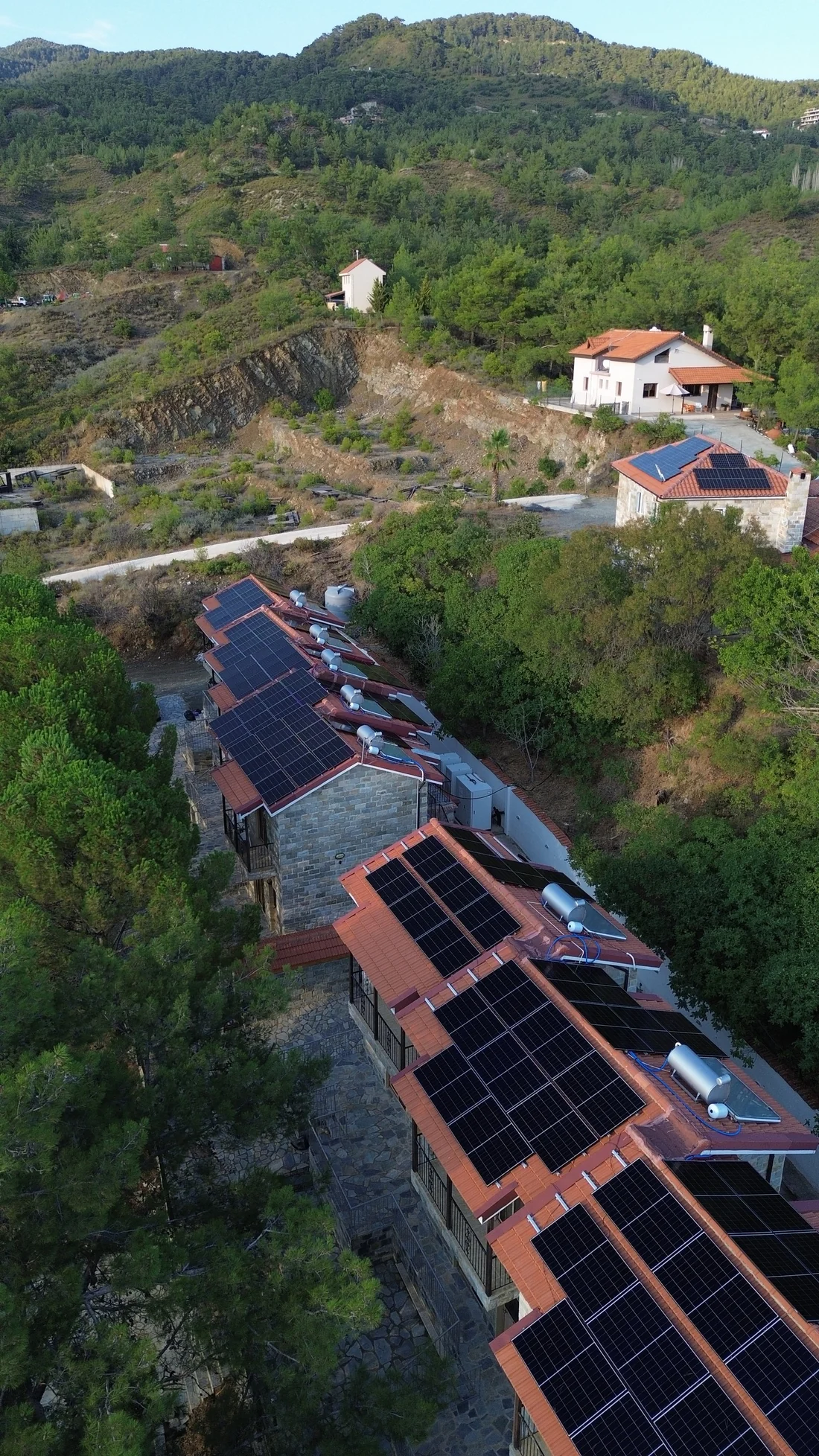 Solar panels on the tiled roofs of the hotel buildings, with the mountains in the background
