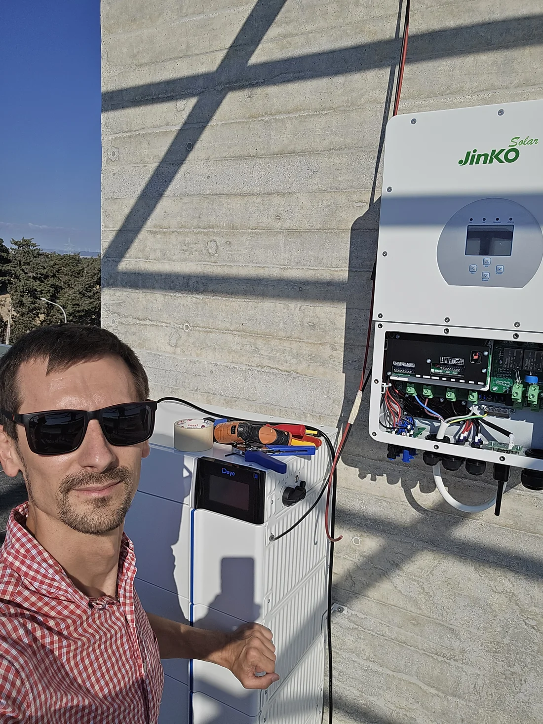 Εκπρόσωπος της UNLIMITED στο ακίνητο δίπλα σε ανοικτό inverter και μπαταρία Deye